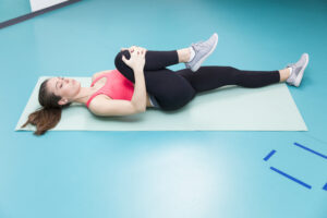 For some patients, bringing one knee gently towards the chest while lying down may provide a comfortable stretch in the lower back.